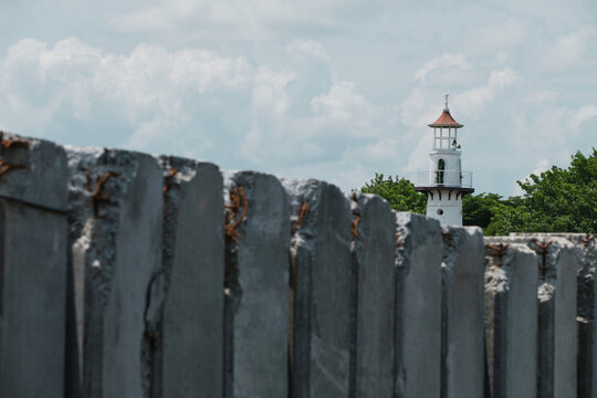 lighthouse behind concrete slabs and cloudy sky
