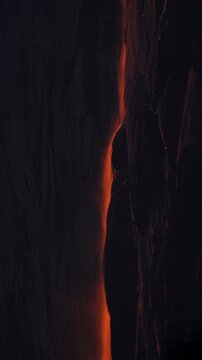 Vertical Screen: Yosemite National Park Firefall phenomenon with glowing orange water cascading down dark granite cliff face at dusk, creating stunning natural lava-like effect
