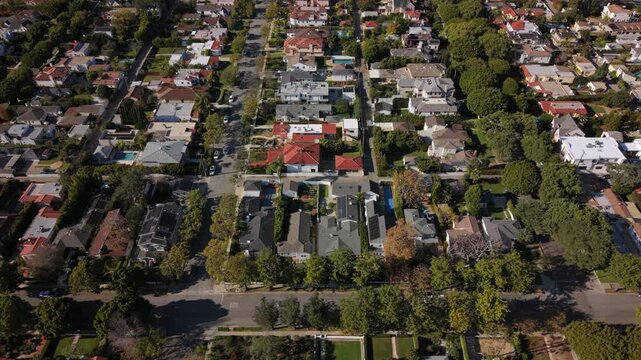 Aerial overview los angeles residential grid with aligned tree rows, mid century homes, pools and neat driveways, drone slowly revealing street network and property patterns ideal