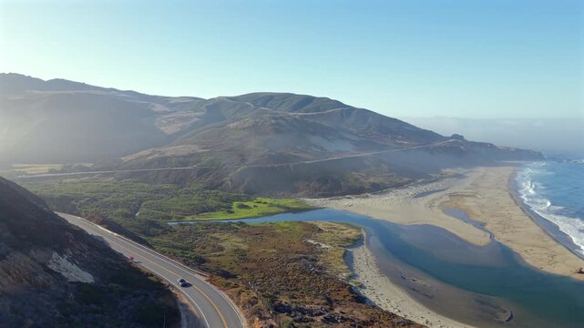 Serene coastal landscape. Quiet estuary meets sandy shores. Peaceful marsh and winding road views. Tranquil journey along winding coast with blue lagoons and lush marshes