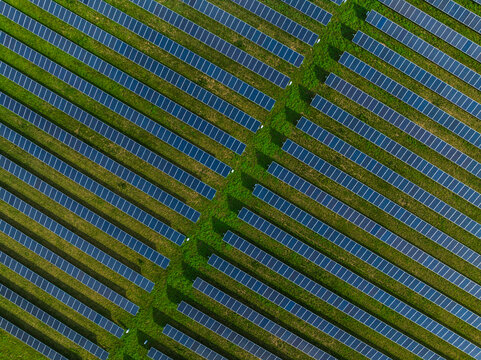 Aerial view of solar panels arranged in diagonal rows on a lush green field in Indianapolis, Indiana, United States.