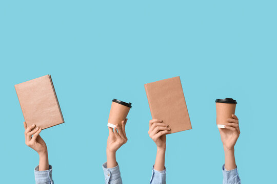 Female hands with books and paper cups of coffee on blue background