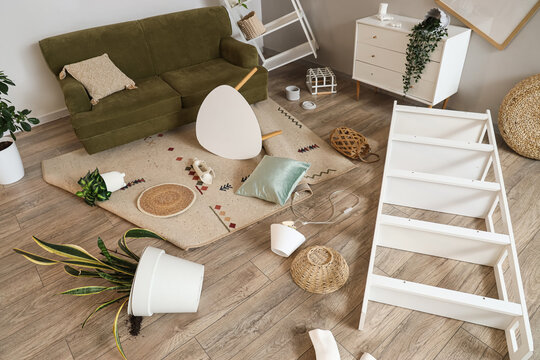 Interior of messy living room with sofa and fallen things after earthquake