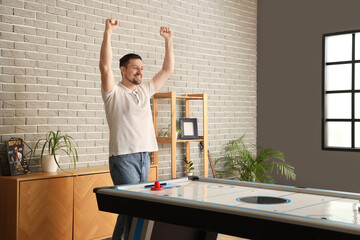 Obraz premium Happy young man playing air hockey at home