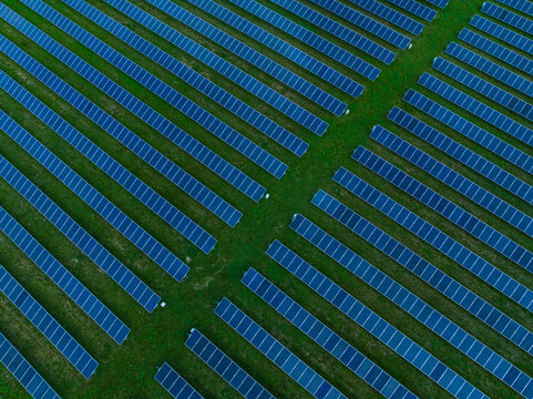 Aerial view of rows of blue solar panels arranged in a geometric pattern on a green field in Indianapolis, Indiana, United States.