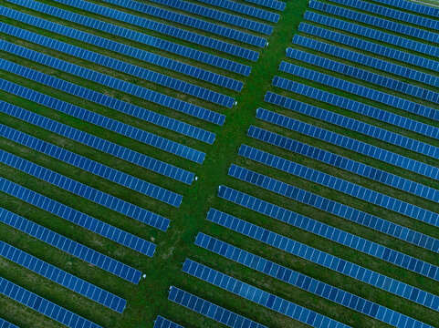 Aerial view of solar panels arranged in neat rows across a green field Indianapolis, Indiana, United States.
