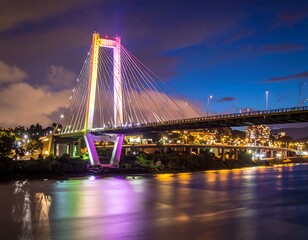 Fototapeta premium Modern cable-stayed bridge lit with colorful lights at dusk