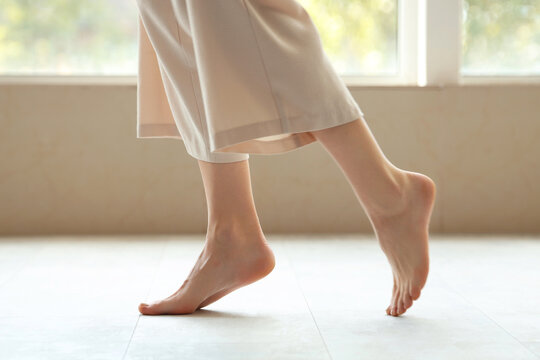 Young woman with flat feet on floor near window at home, closeup