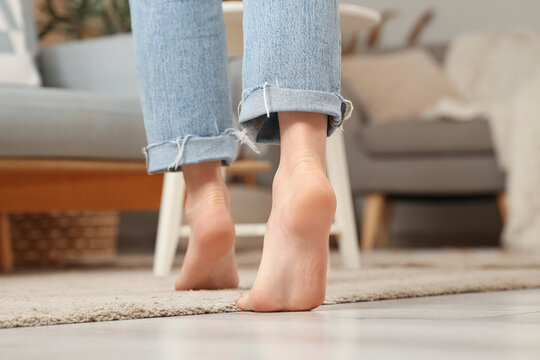 Young woman with flat feet on floor at home, back view
