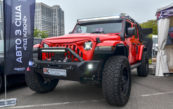 Bright red Jeep Wrangler with an aggressive angry eye grille, massive off-road tires, and extensive LED lighting. Rugged 4x4 built for adventure