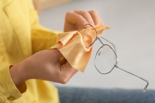 Beautiful young Asian woman wiping eyeglasses at home, closeup