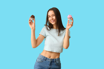 Young woman with sweet cupcakes on blue background. Valentine's Day celebration