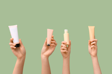 Fototapeta premium Female hands with different cosmetic products on green background