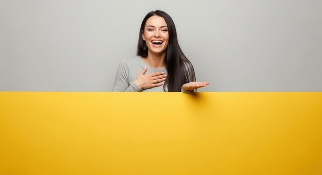 Young woman smiles while presenting a blank yellow banner with her hand.
