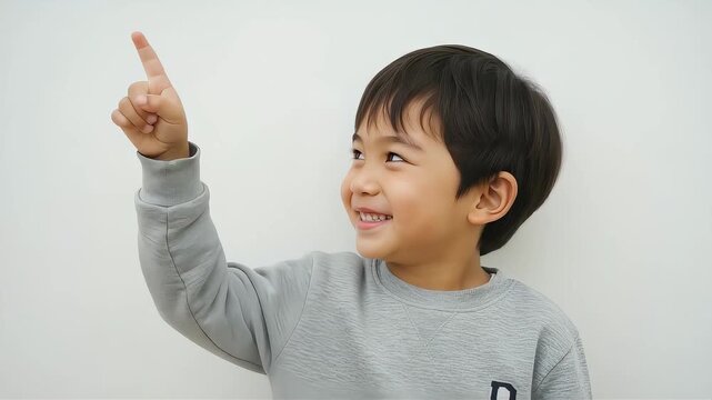 元気いっぱいに上を指差す笑顔の男の子。子供の成長、教育、発見のイメージ素材