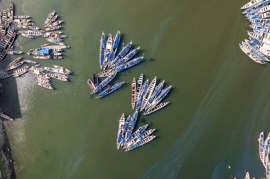 Aerial view of traditional wooden fishing boats clustered in the green waters near Fishing Harbour Road in Tema, Greater Accra Region, Ghana.