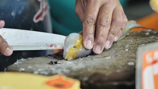 Close Up of hands cutting yellowstripe scad fish in Puerto Princesa market