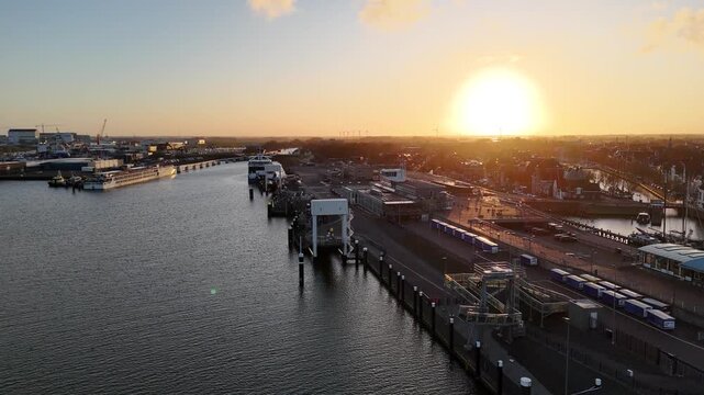 Drone tracks away with the sun behind and the harbor spread across the frame.
