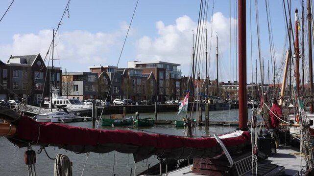 Static harbor composition with tall masts, waving flag and canal side houses.