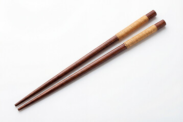 Fototapeta premium Pair of dark brown wooden chopsticks with woven detail on a white background