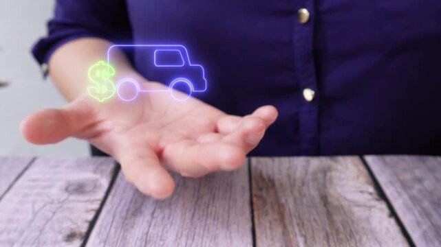 Transportation and Finance. Close-up of a woman's hand at a table holding a virtual van icon with a dollar sign.