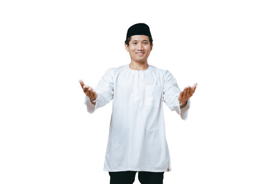 Young Muslim man in white baju kurung and black peci presenting with both open hands to the side against white background