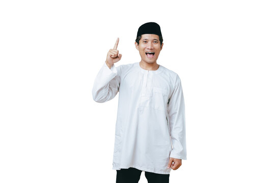 Young Muslim man in white baju kurung and black peci pointing one index finger upward against white background