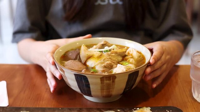 Woman Placing Hands Around a Large Bowl of Vietnamese Pho Soup