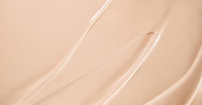Beige liquid foundation creating smooth and creamy cosmetic texture with abstract waves