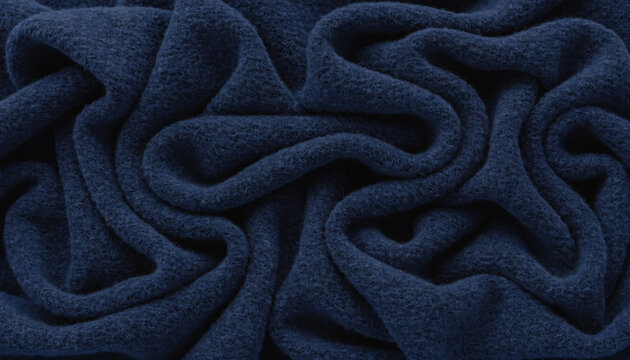 A close-up full frame shot of dark blue fleece fabric with rich texture, crumpled into soft, inviting folds and wrinkles.