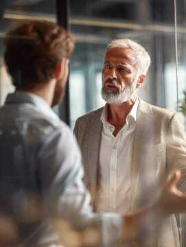 Heavyset CEO and employee having difficult conversation in glass-walled office