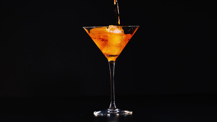Fototapeta premium Orange Aperitif Being Poured into a Cocktail Glass with Ice