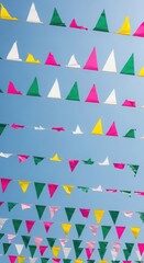 Obraz premium Colorful bunting flags against bright blue sky with multi colored