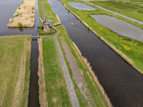 Aerial view of Meerburgermolen windmill standing beside a calm canal and lush green polder fields Leiderdorp, South Holland, Netherlands.