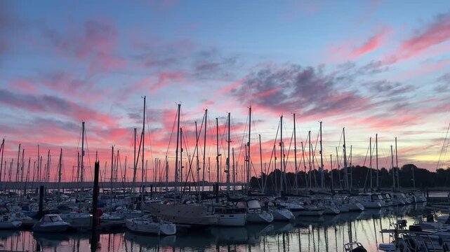 A wide shot captures numerous sailboats docked in Gosport Marina under a stunning pink and blue sunset sky with reflections on the calm water