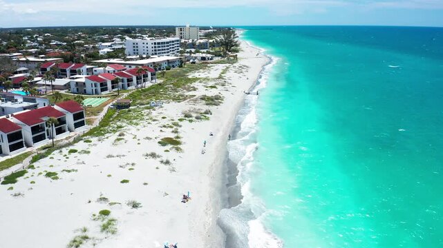 White sands stretch alongside turquoise waters and red-roofed buildings. Ideal for showcasing coastal real estate or travel content.