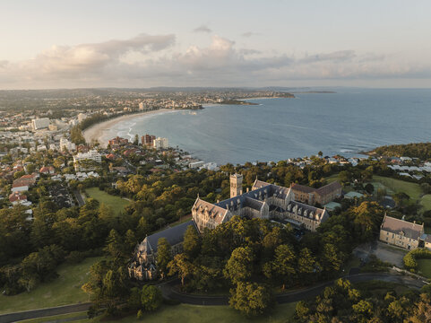 Aerial view of the International College of Management, Sydney building overlooking Manly Beach and the coastline during golden hour in Manly, New South Wales, Australia.