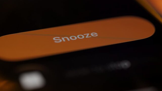 Smartphone alarm screen with snooze button in close up. Concept of oversleeping, morning routine, waking up, and delaying alarm.