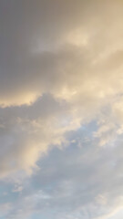 Obraz premium Cloudy sky with warm golden light blending into soft blue tones, creating a calm atmospheric background with gentle natural lighting and subtle texture.