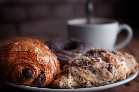 Reposteria fina, pan dulce mexicano para desayuno postres o cenas en familia, tradicional. pan de hojaldre cubierto de laminas de almendra y coco, con pan relleno de chocolate al lado, cafe al fondo.