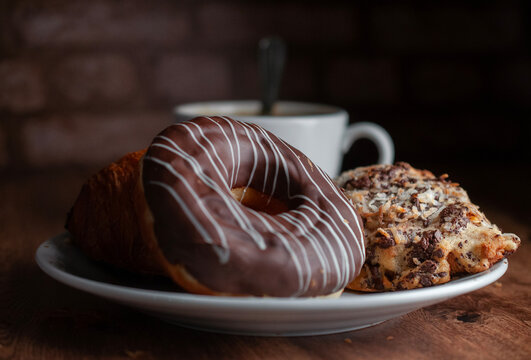Reposteria fina, pan dulce mexicano para desayuno postres o cenas en familia, tradicional. dona de chocolate con pan de hojalde con laminas de almendra y coco con una taza de cafe en el fondo.