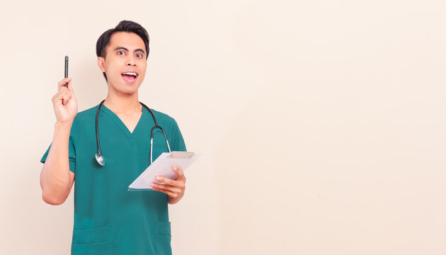 Excited Southeast Asian male nurse or doctor in green scrubs and stethoscope having a great idea or eureka momenton isolated background.