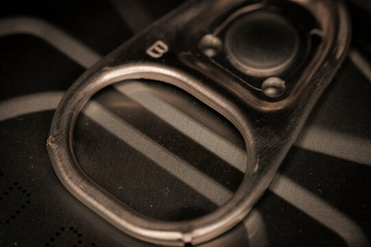 Macro closeup of metal pull tab on food can lid showing ring mechanism and textured surface of sealed container
