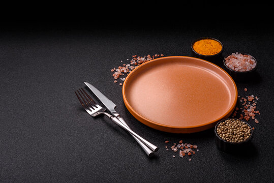 An empty ceramic round plate, kitchen utensils for a dinner table. An empty plate