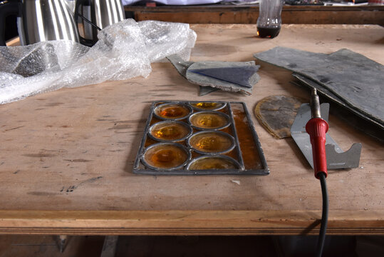 Soldering a traditional amber bullseye stained glass panel on a workbench