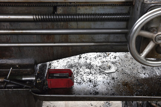 Close-up of industrial metal lathe lead screw and chips tray in a machine shop