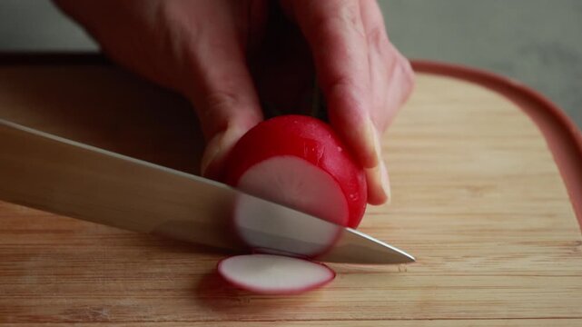 Close-Up of Woman's Hands Thinly Slicing Fresh Radishes on a Wooden Cutting Board