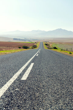 Endless road to horizon through fields and mountains