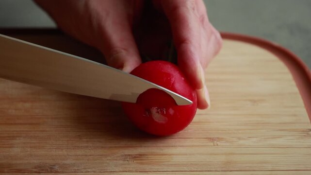 Close-Up of Woman's Hands Thinly Slicing Fresh Radishes on a Wooden Cutting Board
