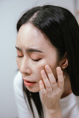 Fototapeta premium A worried woman touching her face while looking in the mirror, concerned about skin aging, wrinkles, and facial imperfections in a close-up beauty and skincare concept.